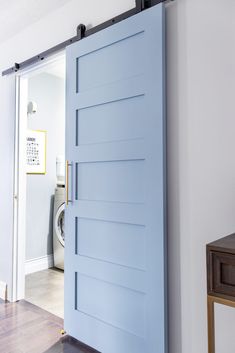 a blue door is opened to reveal a washer and dryer in the background