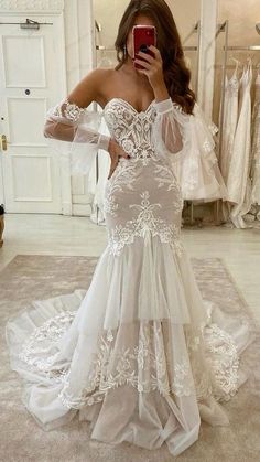 a woman taking a selfie while wearing a wedding dress in front of a mirror