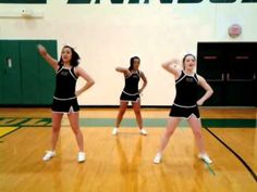 three cheerleaders in black and white outfits are dancing on a basketball court with their hands up