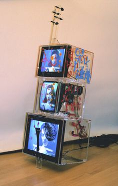 a stack of televisions sitting on top of a wooden floor next to a wall