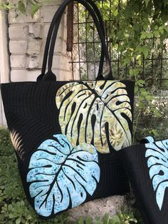 two black and blue purses sitting on top of a stone bench next to a tree