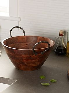 a wooden bowl sitting on top of a counter next to bottles and other kitchen items