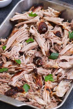 a pan filled with meat and garnishes on top of a blue table