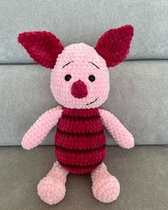 a pink and red stuffed animal sitting on top of a couch