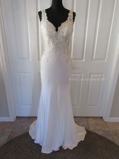 a white wedding dress on a mannequin in front of a door with a black top