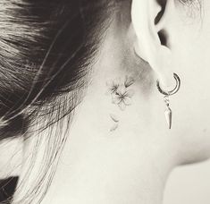 a woman's left ear is adorned with small flowers and a crescent shaped knife