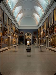 an art gallery with many paintings on the walls and tables in front of each other