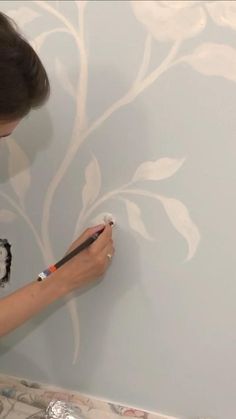 a woman is painting a wall with white paint