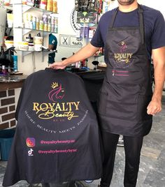 a man standing next to a table with a black apron on it