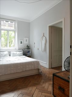 a bedroom with white walls and wood flooring