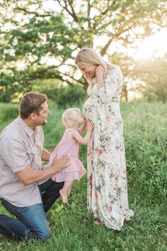 a mother and father hold their daughter's hand as they sit in the grass