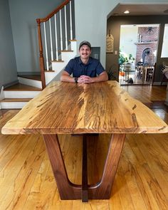 a man sitting at a wooden table in the middle of a room with hardwood floors