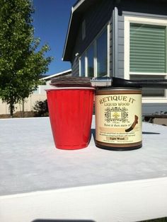 a red cup sitting on top of a white table next to a jar of liquid