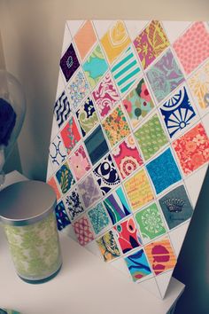 a white table topped with a cup filled with liquid next to a colorful wall hanging