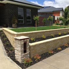 a stone wall and flower bed in front of a house