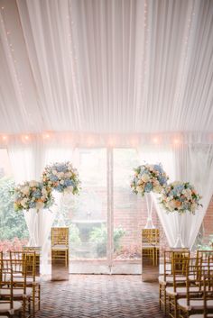 the ceremony room is decorated with white draping and gold chairs, blue and pink flowers in vases