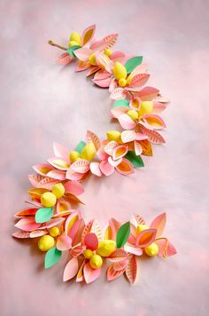 paper flowers are arranged in the shape of an oar on a pink background with yellow and green leaves