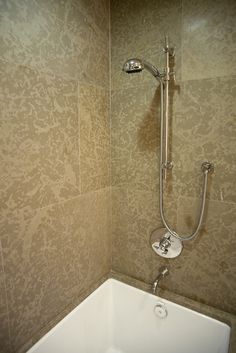 the shower head is attached to the wall above the bathtub in this tiled bathroom