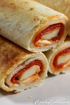 two burritos cut in half sitting on a plate next to some ketchup