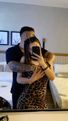 a man and woman taking a selfie in front of a mirror with their arms around each other