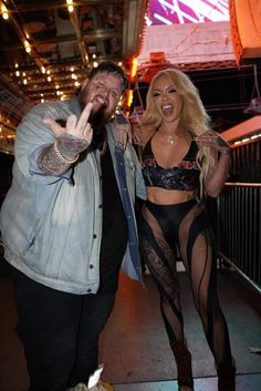 two people standing next to each other in front of a stage with lights and signs