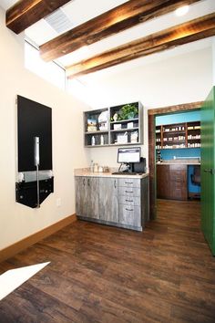 a room with wooden floors and white walls, has a large open cabinet on the wall