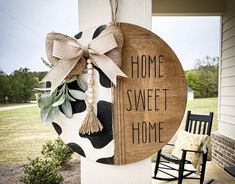 a wooden sign that says home sweet home hanging on the side of a house next to a rocking chair