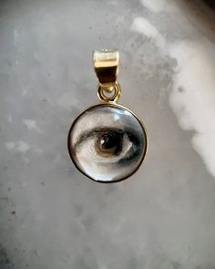 Lover's Eye pendant with an oil painting encased in gold plate over sterling with a quartz crystal cabochon which gives a magical magnifying effect, measuring 1/2" in diameter; 18" 16k gold over brass chain included. THE HISTORY: Lover's Eyes were a jewelry trend c.1785-1830 of brooches set with tiny watercolor portraits on ivory. Since they were cropped to eyes, they were in many ways more direct and intimate than traditional miniature portraits; but also because they were just eyes, they were Mystical 14k Gold Jewelry Gift, Mystical 14k Gold Jewelry, Mystical Clear Jewelry For Gifts, Mystical Engraved Gold Jewelry, Spiritual Gold Cabochon Necklace, Artistic Gold Jewelry With Cabochon, Gold Spiritual Necklace With Cabochon, Spiritual Gold Necklace With Cabochon, Artistic Gold Sterling Silver Necklace