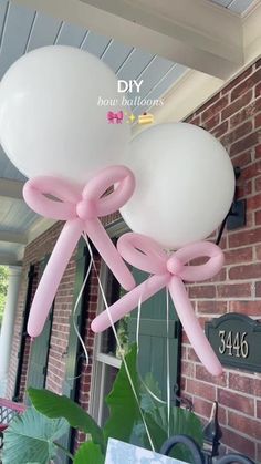 two balloons attached to the side of a brick building with ribbon and bows on them