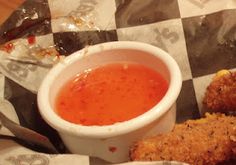 some fried food is sitting on a checkered table cloth with a cup of sauce