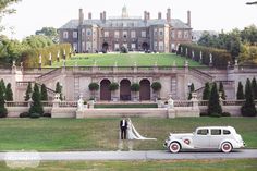 a bride and groom standing in front of an old mansion