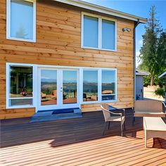 a wooden deck with chairs and tables next to a house that is built into the side of a mountain