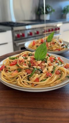 two plates filled with pasta and vegetables on top of a wooden table