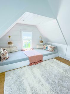 an attic bedroom with white walls and wood flooring is decorated in pastel tones