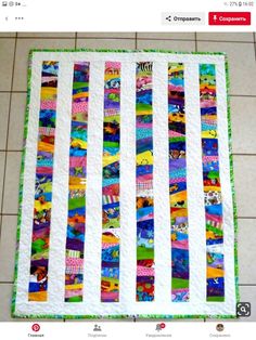 a close up of a colorful quilt on the floor with white tiles in the background