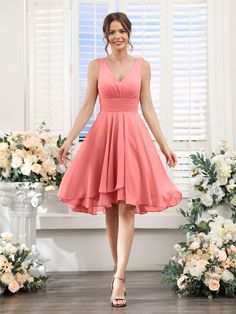 a woman standing in front of flowers wearing a pink bridesmaid dress and heels