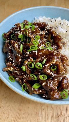 a blue plate topped with rice and meat covered in sesame seed sprinkles