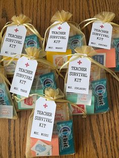 six teacher survival kits are wrapped in twine and tied with gold ribbon on a wooden table