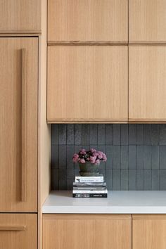 a vase filled with flowers sitting on top of a white counter next to wooden cabinets