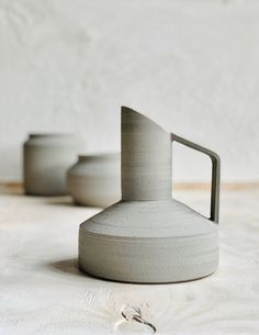 three white vases sitting next to each other on a table