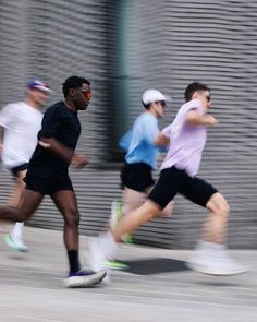 three men running down the street in front of a metal wall with shutters on it