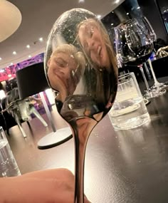 a person holding a wine glass with two people in it