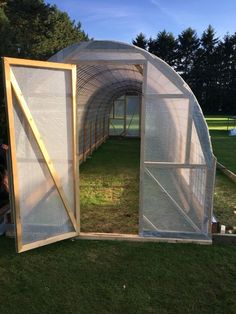 a small greenhouse with the doors open and grass growing inside