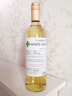 a bottle of white wine sitting on top of a table next to a wallpaper