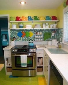 a kitchen with yellow walls and green flooring, white countertops and stainless steel appliances