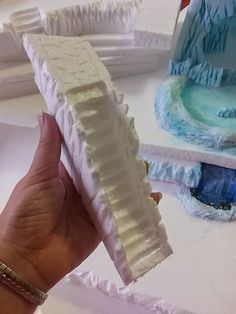 a hand holding a piece of cake that looks like it is made out of icing