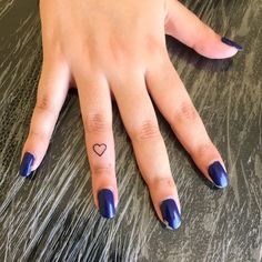 a woman's hand with blue nail polish and heart tattoo