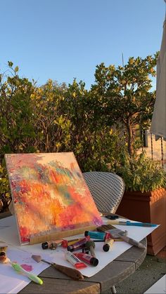 an easel is sitting on a table with paint and other art supplies in front of it