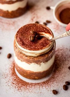 someone is spooning out some kind of dessert in a jar with coffee beans on the side