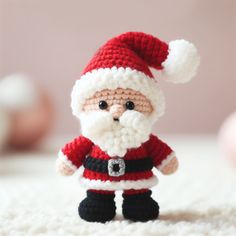 a small crocheted santa clause is standing on the carpet